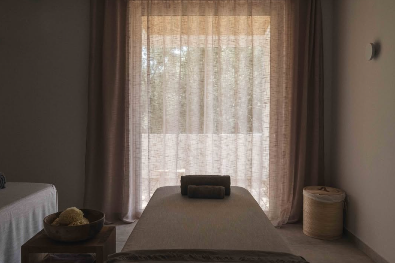 Calm treatment room with a massage table and soft curtains