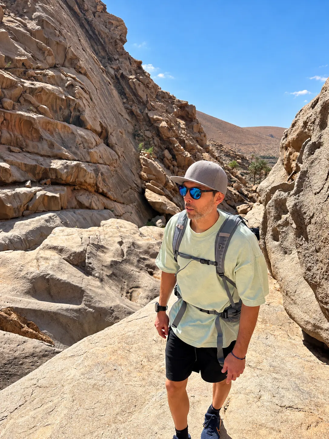 Vasilis hiking through a rocky gorge in bright sunlight