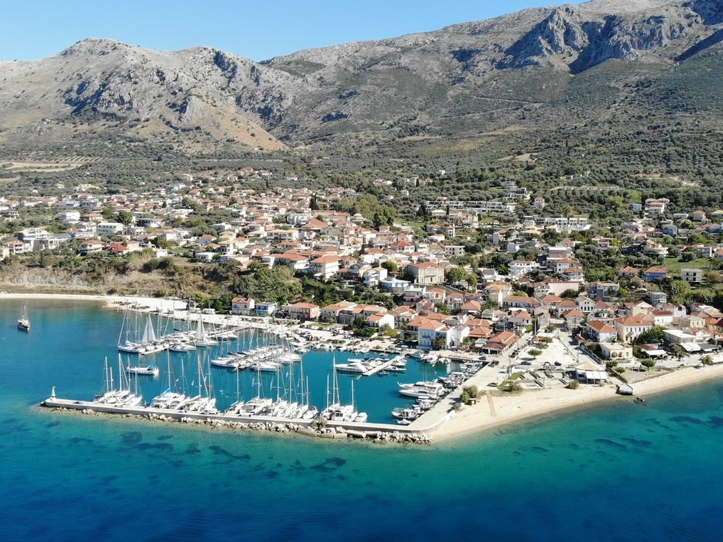 Aerial view of Paleros harbour with the sandy beach spit, moored boats and the village rising behind
